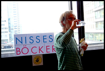 Nisse dricker vatten framfr skylt med Nisses bcker