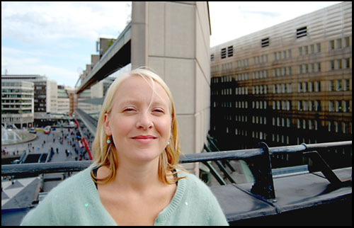 Julia Falkerby i ljusbl kofta med utsikt mot Sergels torg och baksidan av Kulturhuset