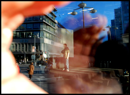 utsikt genom Kulturhusets fnster, fotografens hand och objektivet speglar sig